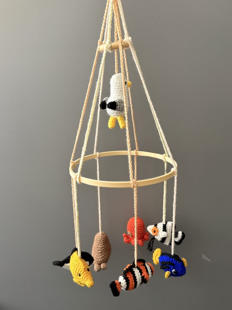 handmade crochet baby mobile featuring whales, seals, fish, and octopus toys
