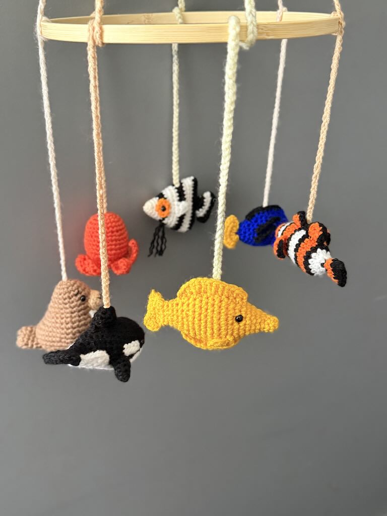 handmade crochet baby mobile featuring whales, seals, fish, and octopus toys