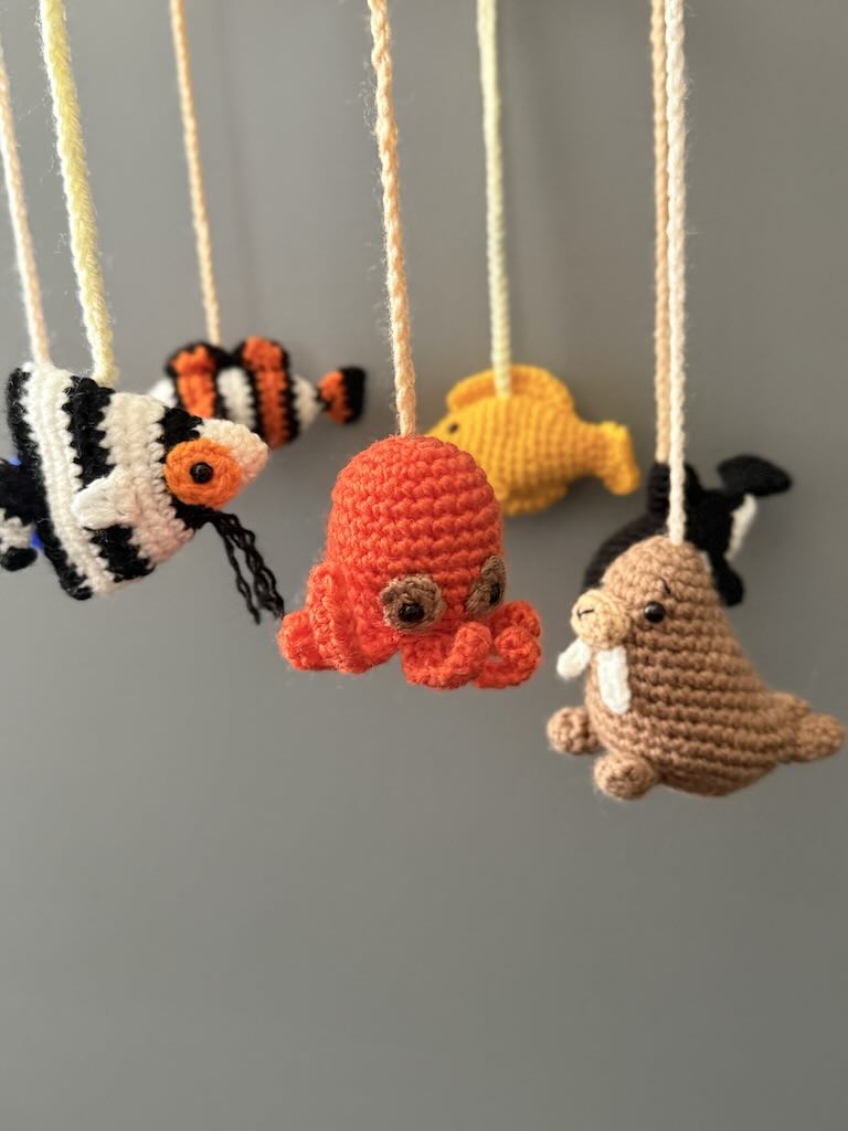 handmade crochet baby mobile featuring whales, seals, fish, and octopus toys