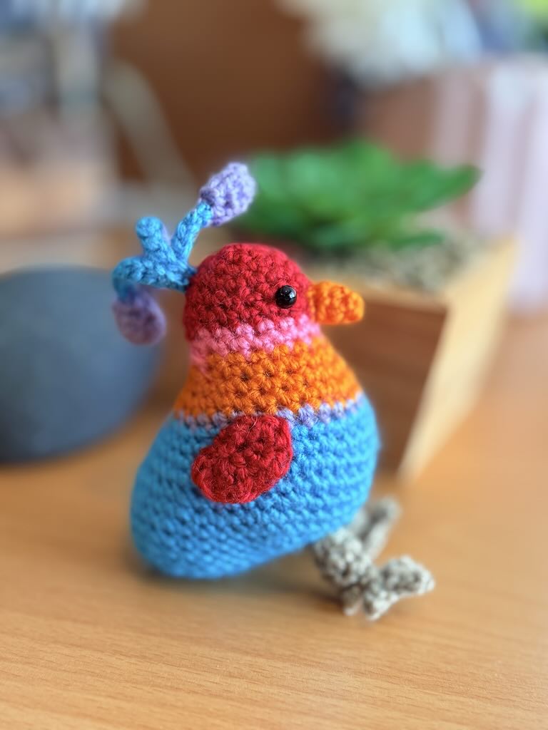 handmade crochet songbird with cheerful colours and soft wings