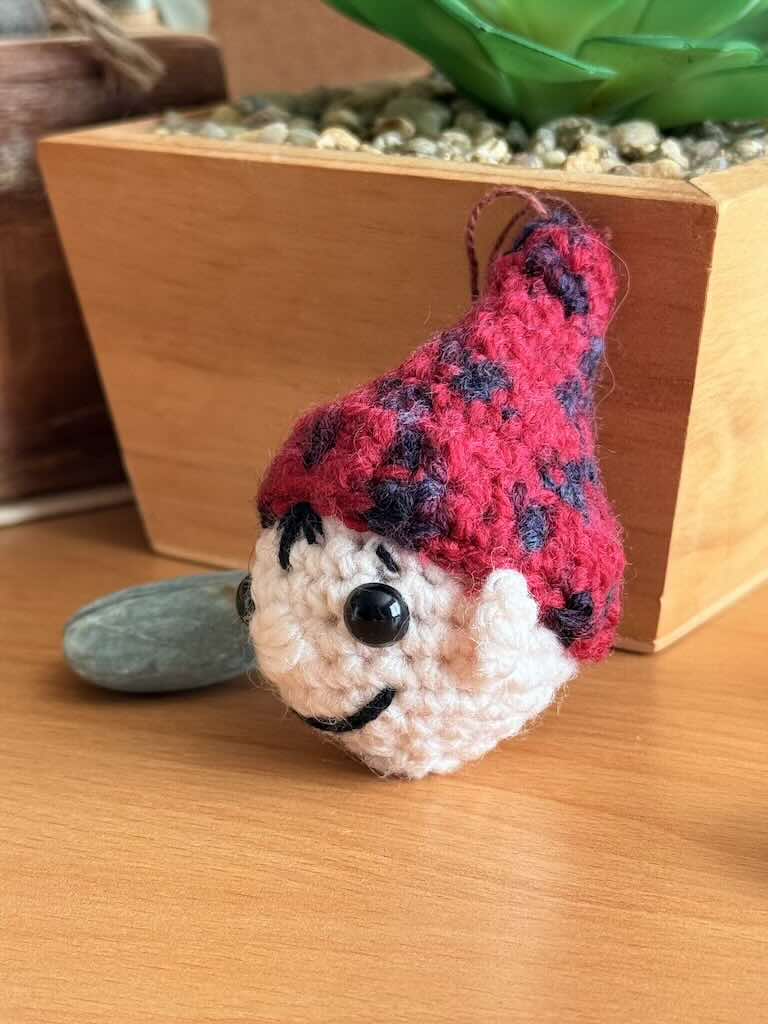 cute handmade crochet Christmas elf decoration with red and black hat