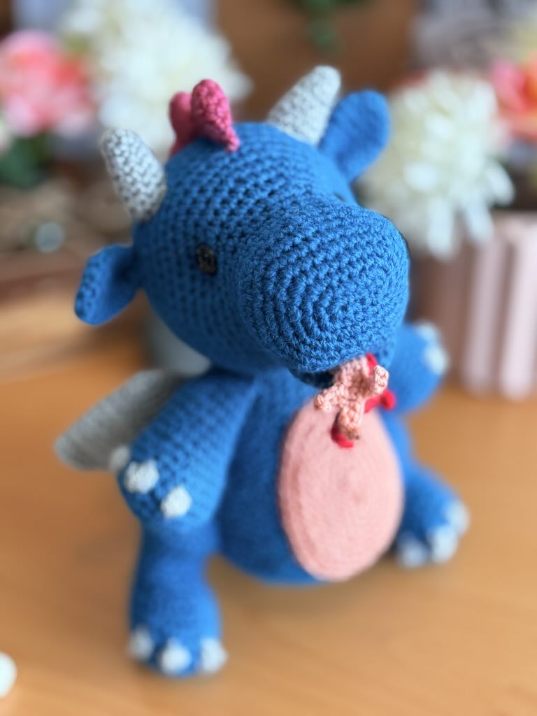 crochet fire-breathing dragon toy with pink tummy and cheerful expression