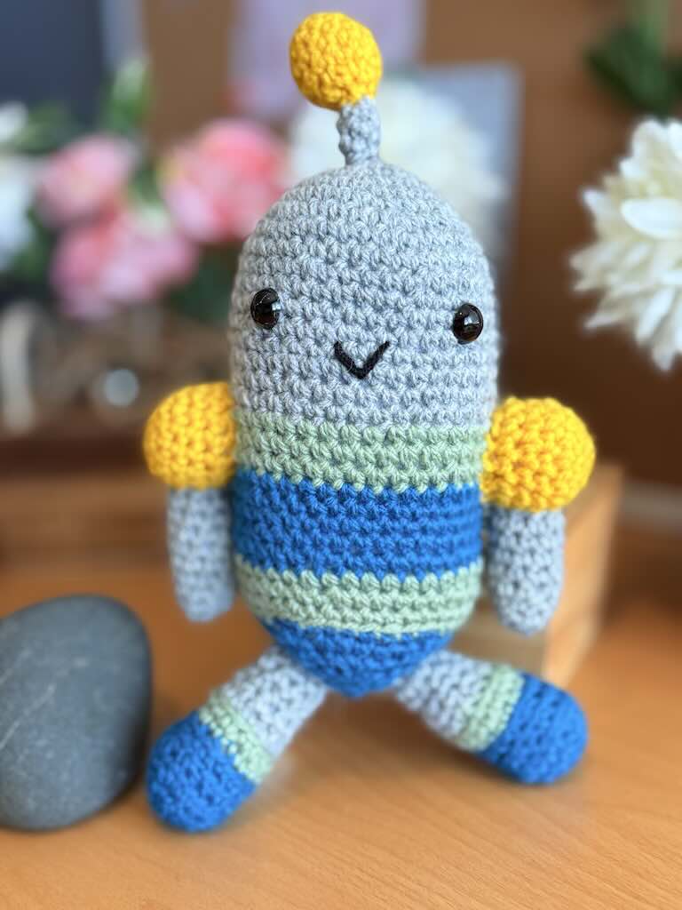 crochet robot toy named Robby with colorful yarn and crochet mechanical arms