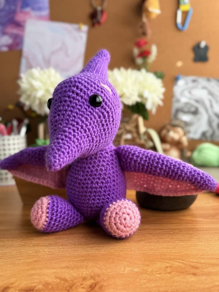 handmade crochet flying pterosaur toy named Pip with purple body and wide wings